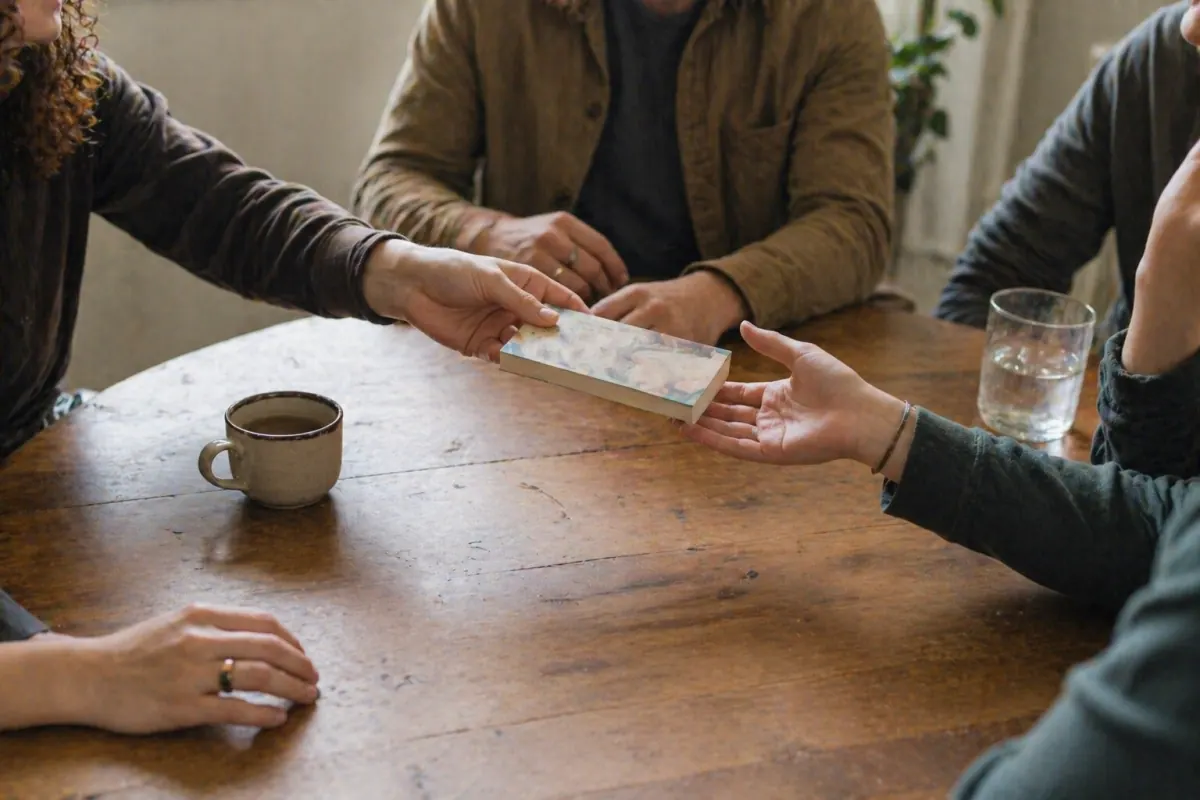 People passing an item around a table during a group discussion
