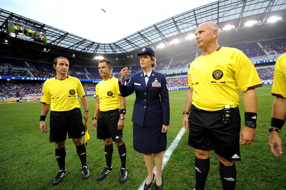 A coin toss before a soccer match kickoff with officials on the field
